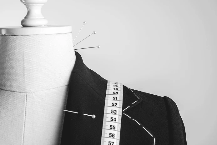 トルソーに黒いジャケットを着せ、肩にメジャーを掛けた裁縫作業の様子